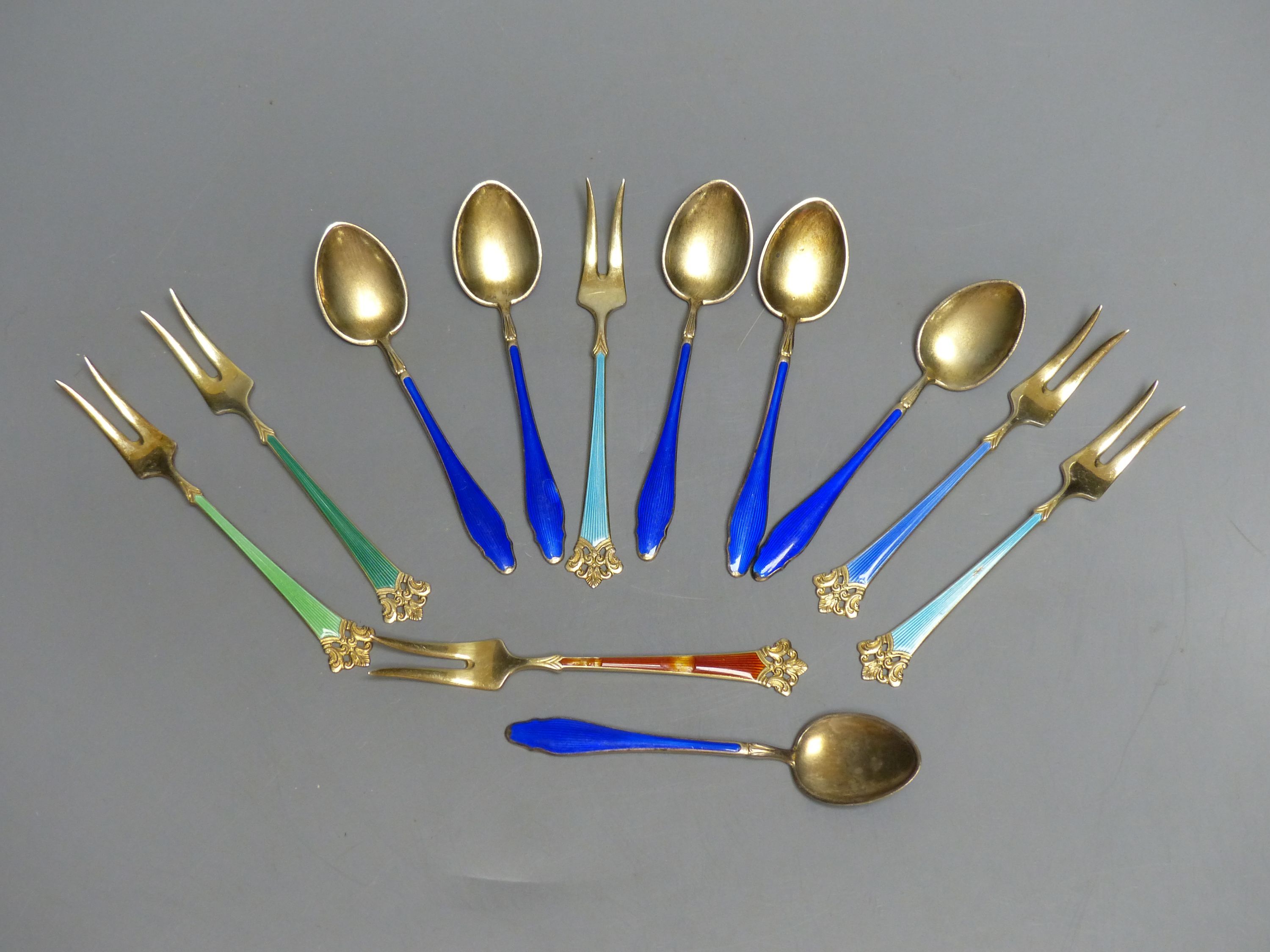 Six Norwegian sterling gilt and enamel small forks and six sterling and blue enamel coffee spoons.